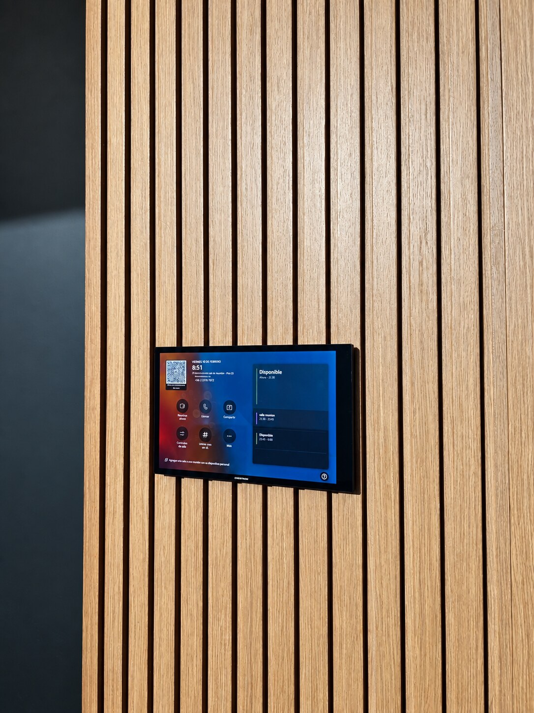 Panel táctil mural que muestra la disponibilidad y opciones de uso de una sala de reuniones.